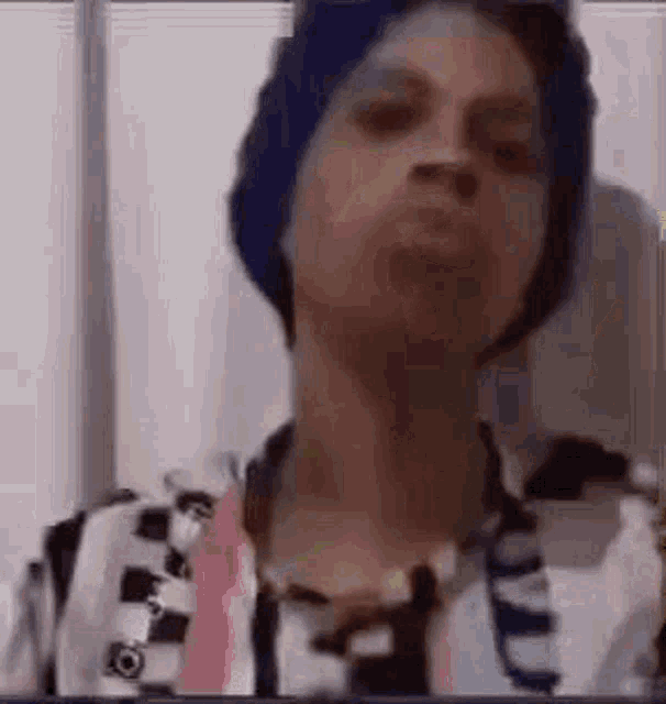 a man wearing a blue hat and a striped shirt is making a funny face .