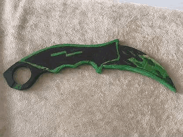 a green and black knife is sitting on a towel on a bed .