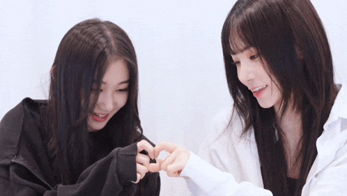 two girls are making a heart with their fingers