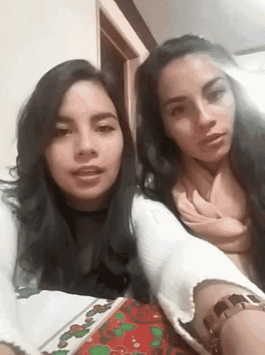 two women are sitting at a table with a christmas wrapping paper on it