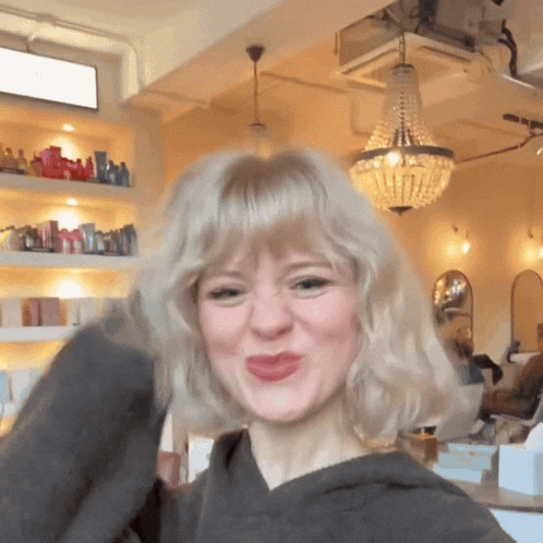 a woman with blonde hair is making a face in a salon