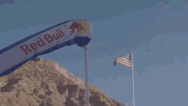 a red bull banner is blowing in the wind near an american flag