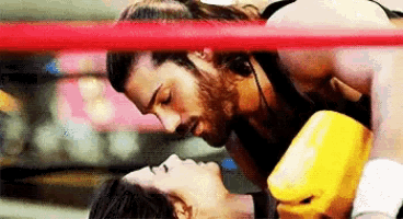 a man and woman kissing in a boxing ring .