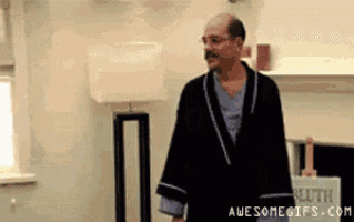 a bald man in a robe is standing in a living room