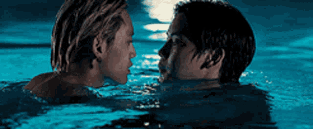 a man and a woman are kissing in a pool at night