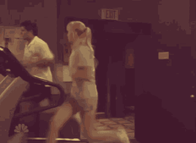 a blurred image of people in a gym with an exit sign
