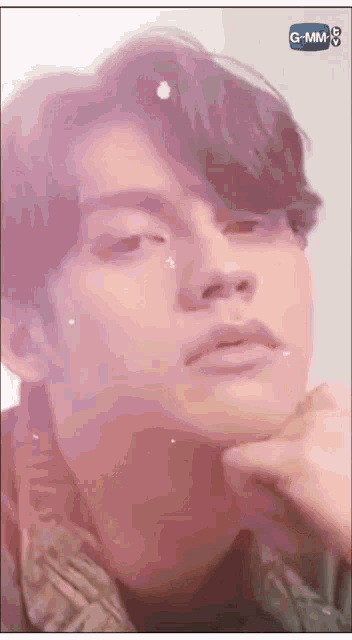 a close up of a young man 's face with a g-mm logo in the corner