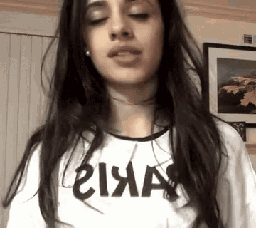 a woman with long dark hair is wearing a white t-shirt with the word akira written on it .