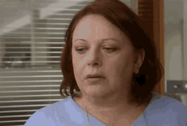 a woman with red hair is wearing a blue scrub