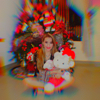 a woman is sitting on the floor holding a hello kitty stuffed animal