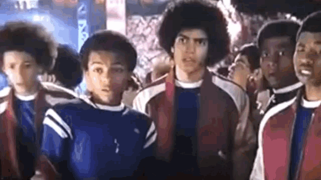a group of young men are standing next to each other in a crowd and looking at the camera .