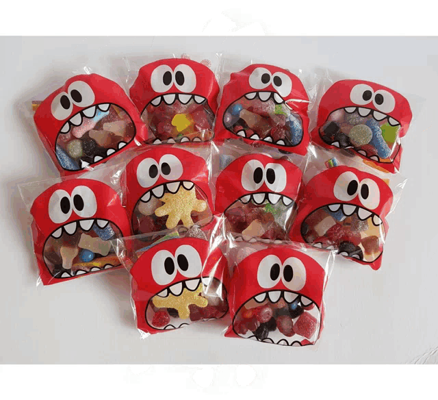 a bunch of red bags with cartoon faces on them are filled with candy
