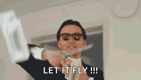 a man in a suit and sunglasses is holding a bunch of money and says let it fly