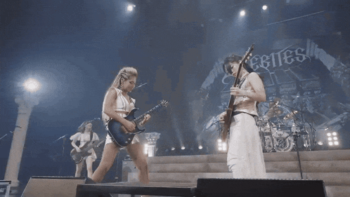 a woman playing a guitar on a stage with a banner that says ebites
