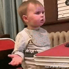a baby is sitting at a table making a funny face .