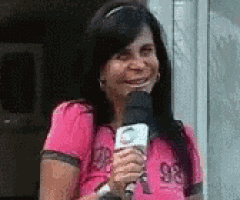 a woman in a pink shirt is holding a microphone
