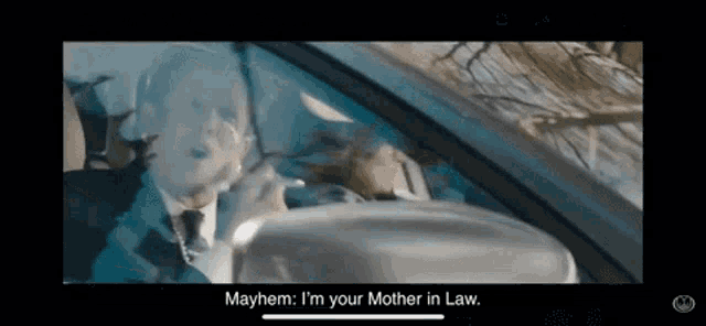 a man in a suit and tie is driving a car and says mayhem i 'm your mother in law .