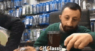 a man with a beard is sitting at a table with a glass of beer in front of him .