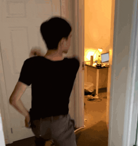 a man in a black shirt is walking through a door