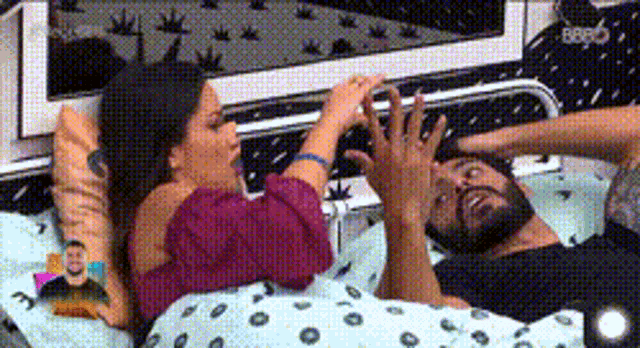 a man and a woman are laying in a bed with their hands on their faces .