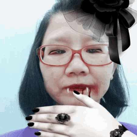 a woman wearing glasses and black nails has blood dripping from her mouth .