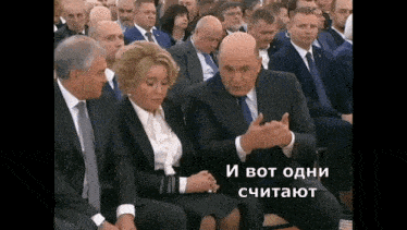 a man in a suit is talking to a woman in a crowd