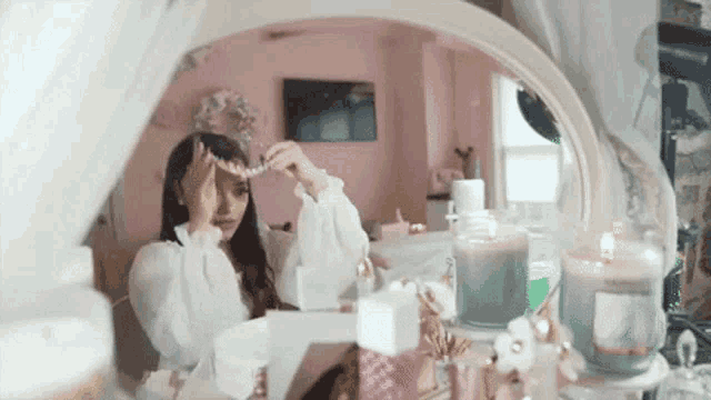 a woman is looking at herself in a mirror while wearing a necklace .