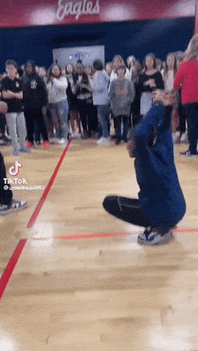 a group of people are gathered in a gym with eagles on the wall