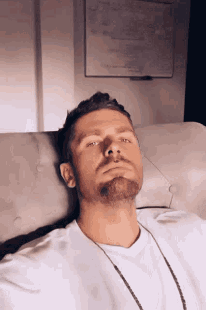 a man with a beard is laying on a bed with his eyes closed