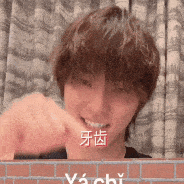 a man is brushing his teeth in front of a brick wall that says ya chi