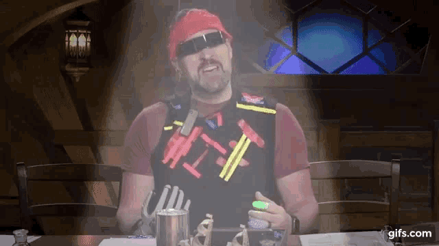 a man wearing a vest that says # 1f is sitting at a table in front of a stained glass window
