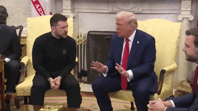 a man in a black shirt sits next to a man in a suit and tie