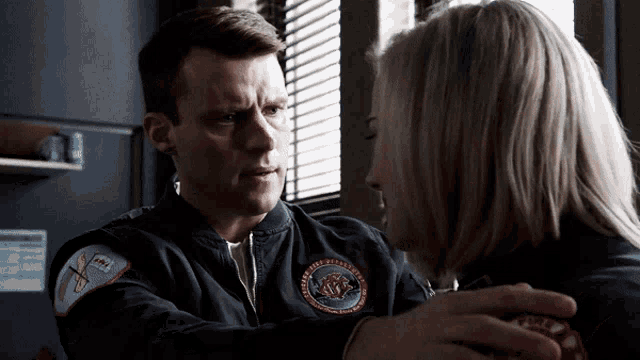 a man and a woman are looking at each other and the man is wearing a jacket that says chicago fire department