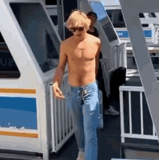 a man without a shirt is walking out of a boat .