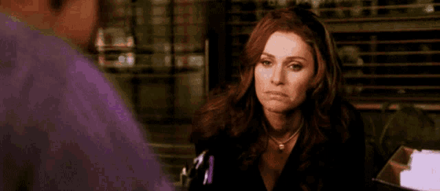 a woman is making a sad face while talking to a man in a purple shirt