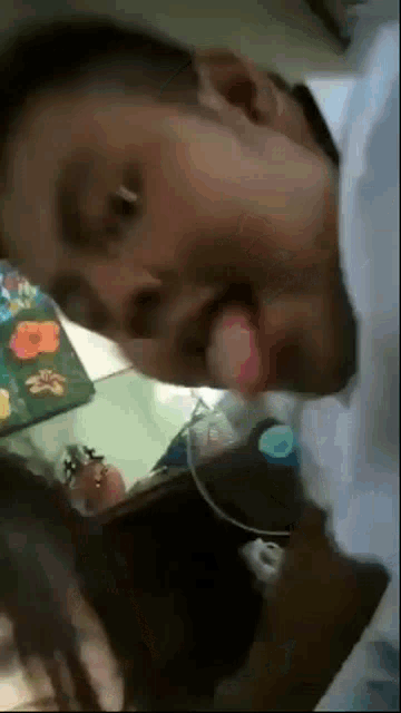 a man is sticking his tongue out while sitting next to a woman on a bed .