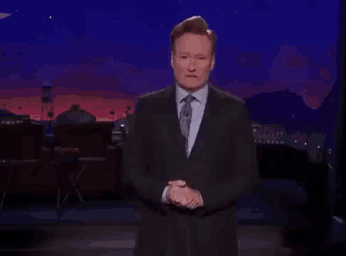 a man in a suit and tie is giving a speech on a stage .
