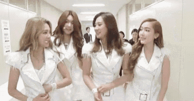 a group of young women are standing next to each other in a hallway and smiling .