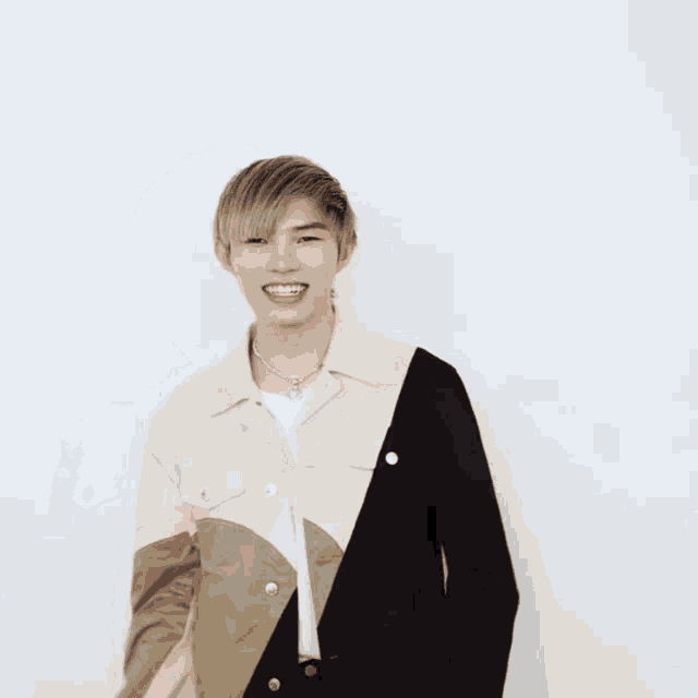 a young man wearing a black and white jacket smiles