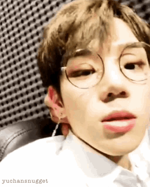 a close up of a boy wearing glasses and earrings .
