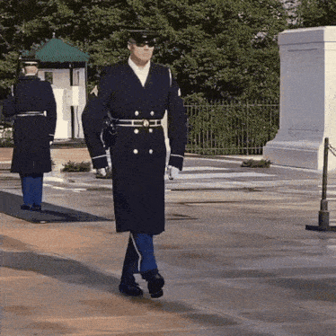 a man in a military uniform is walking in front of a fence
