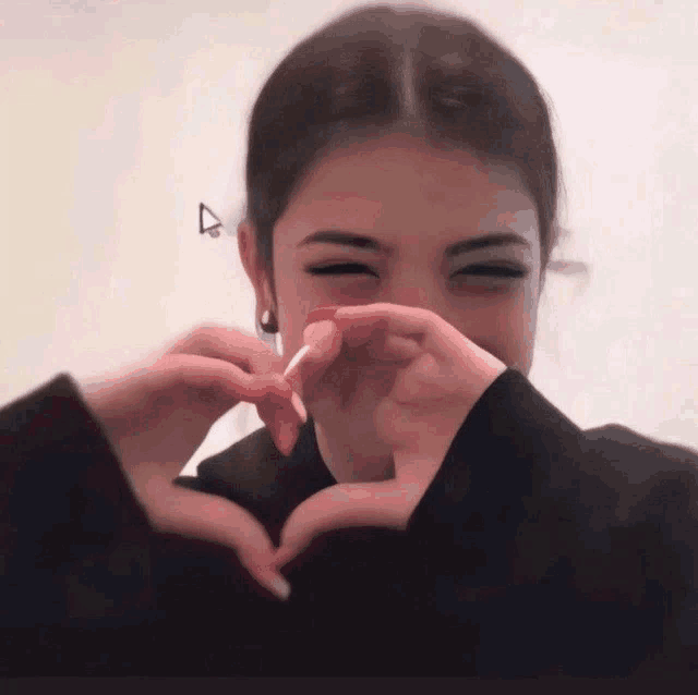 a girl making a heart with her hands and a lollipop