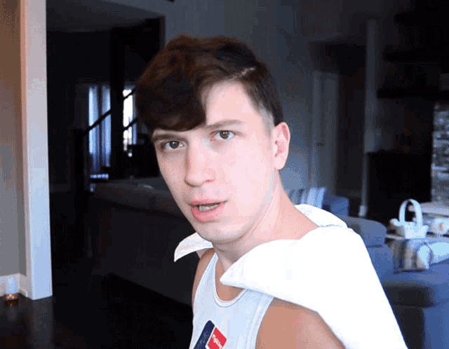 a young man wearing a white tank top with a tommy hilfiger logo