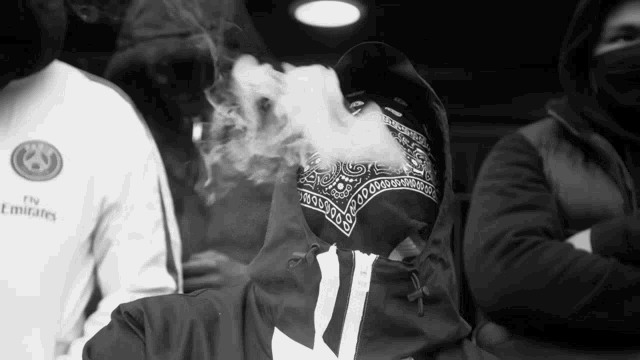 a man wearing a bandana smoking a cigarette in a black and white photo