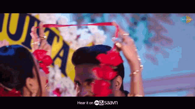 a woman is holding a red ribbon over a man 's head ..