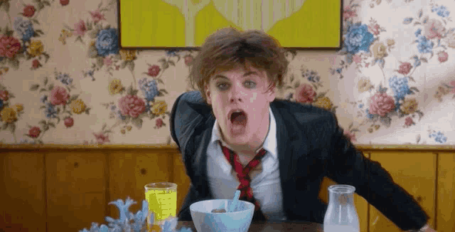 a man in a suit and tie is sitting at a table with a bowl of cereal ..