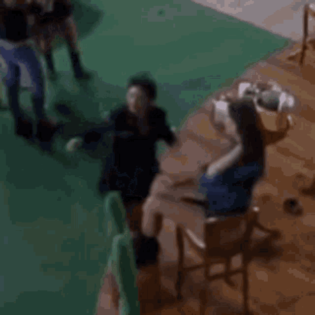 a blurry picture of a group of people standing around a table with a green carpet .
