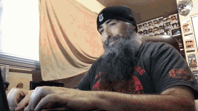 a man with a beard wearing a black beanie and a t-shirt that says fire