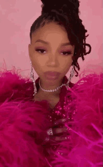 a woman wearing a pink feathered coat and earrings