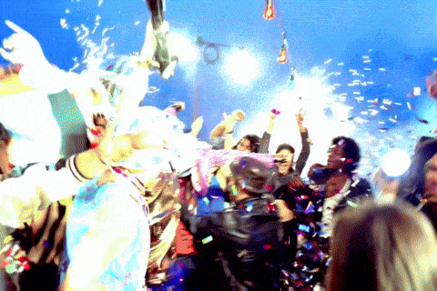 a crowd of people at a party with confetti being thrown